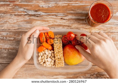 healthy eating, dieting and people concept - close up of woman hands with food in plastic container and fresh tomato juice at home kitchen