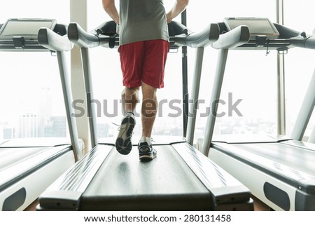 sport, fitness, technology and people concept - close up of male legs running on treadmill in gym