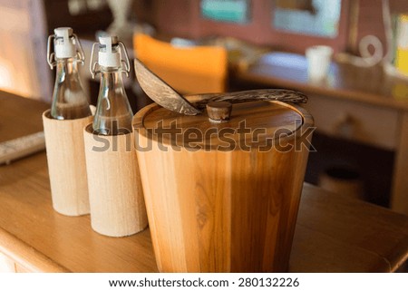 tableware and kitchenware concept - couple of bottles and wooden bucket with spoon on table at hotel room