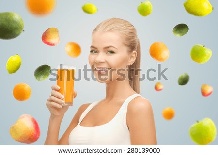 healthy eating, diet, detox and people concept - happy young woman holding glass of orange juice over gray background with falling fruits