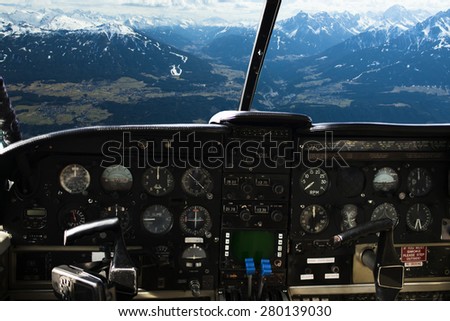 air transport, travel, technology and aviation concept - dashboard in airplane cockpit and view of snowy alps mountains behind windshield