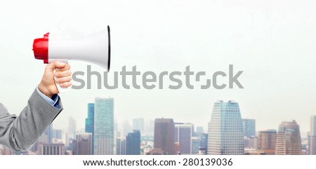 business, people and public announcement concept - close up of male hand in suit with megaphone over city background