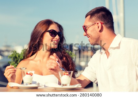 love, dating, people and food concept - smiling couple smiling couple wearing sunglasses eating dessert and looking to each other at cafe