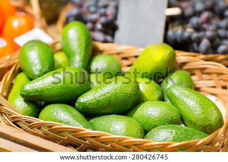 sale, shopping, vitamin c and eco food concept - ripe avocado in basket at food market