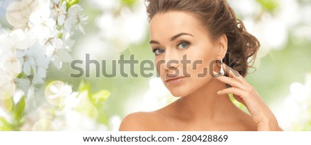 people, beauty, jewelry and accessories concept - beautiful woman with diamond earrings over summer garden and cherry blossom background