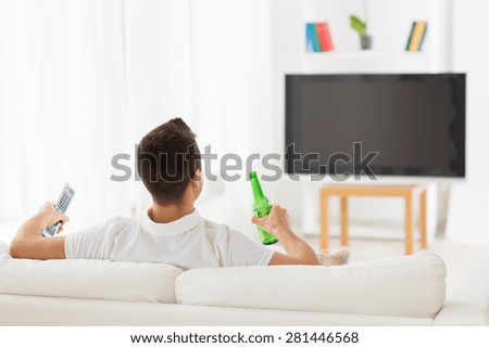 leisure, technology, mass media and people concept - man watching tv and drinking bottle beer at home from back