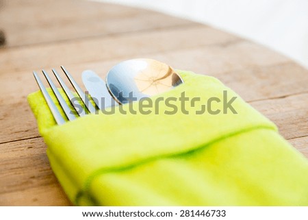 table setting, silverware and eating concept - close up of cutlery set wrapped to napkin on restaurant table