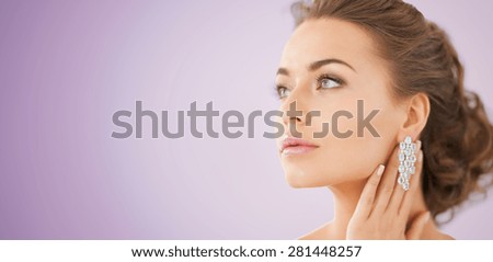 people, beauty, jewelry and accessories concept - beautiful woman with diamond earrings over violet background