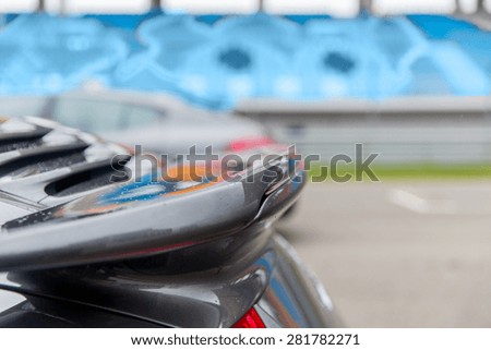 racing, motosports, extreme and motoring concept - close up of sports car back spoiler on speedway of stadium