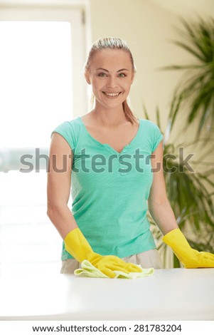 people, housework and housekeeping concept - happy woman cleaning table at home kitchen