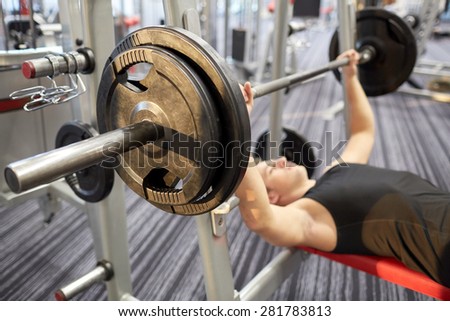 sport, bodybuilding, lifestyle and people concept - close up of man flexing biceps with barbell in gym