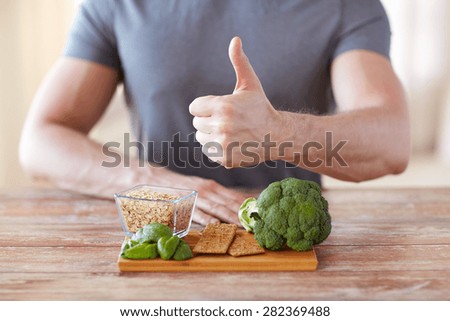 healthy eating, diet, gesture and people concept - close up of male hands showing thumbs up with food rich in fiber
