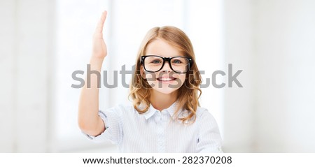 education and school concept - little student girl studying and raising hand at school