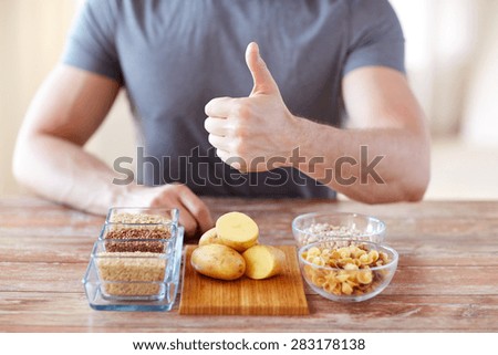 healthy eating, diet, gesture and people concept - close up of male hands showing thumbs up with carbohydrate food on table