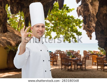 cooking, profession, gesture and people concept - happy male chef cook showing ok sign over restaurant lounge on beach