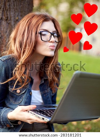 education, flirting, distant relationship, virtual communication and love concept - happy student girl with laptop computer sending air kiss at campus