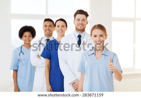 international, profession, people and medicine concept - group of happy doctors and nurses at hospital showing thumbs up gesture