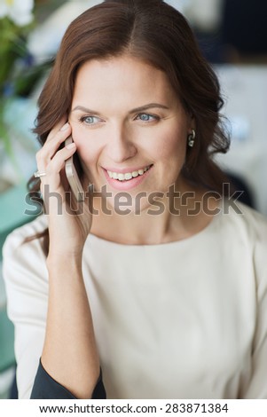 people, women, business and lifestyle concept - happy woman calling on smart phone at restaurant