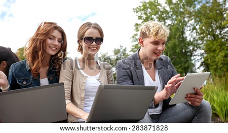 summer, communication, technology , education and teenage concept - group of students or teenagers with laptop and tablet pc computers at park or campus