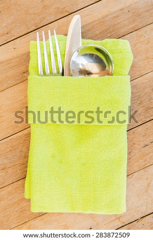 table setting, silverware and eating concept - close up of cutlery set wrapped to napkin on restaurant table