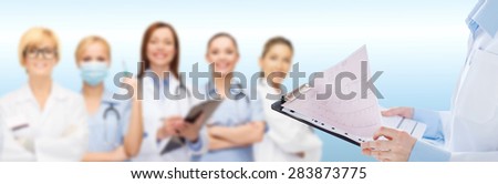 healthcare, cardiology, people and medicine concept - close up of female holding clipboard with cardiogram over medical team