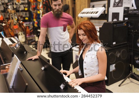 music, sale, people, musical instruments and entertainment concept - happy man and woman playing piano at music store