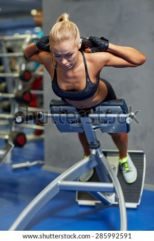 sport, training, fitness, lifestyle and people concept - young woman flexing back and abdominal muscles on bench in gym