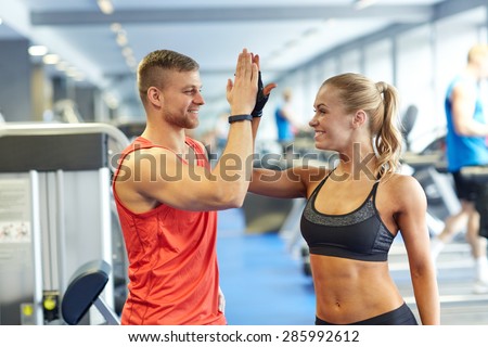 sport, fitness, lifestyle, gesture and people concept - smiling man and woman doing high five in gym