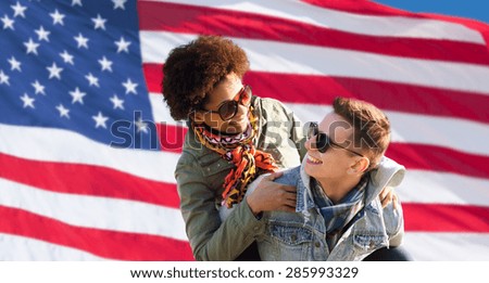 international friendship, freedom and people concept - happy teenage couple in shades having fun over american flag background