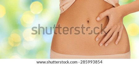 health, digestion, beauty, people and weigh loss concept - close up of woman pointing finger to belly over green lights background