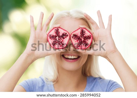 healthy eating, organic food, fruit diet, comic and people concept - happy woman having fun and covering her eyes with pomegranate over green natural background