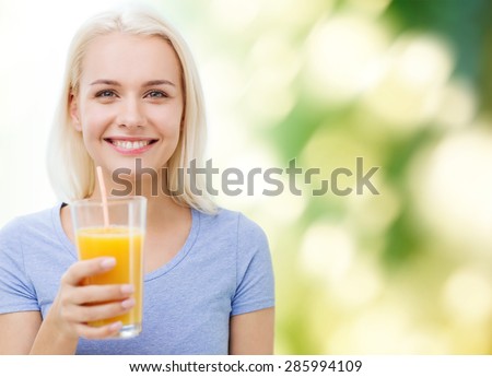 healthy eating, vegetarian food, diet, detox and people concept - smiling woman drinking orange juice or shake from glass over green natural background