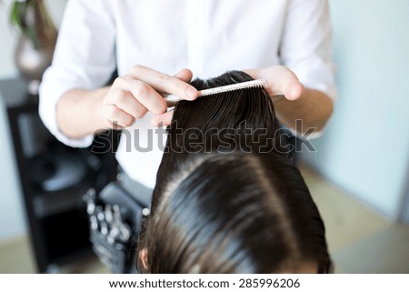 beauty, hairstyle and people concept - close up of male stylist hands combing wet hair at salon