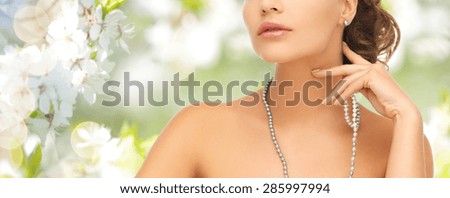 fashion, style, jewelry, beauty and people concept - beautiful woman wearing pearl earrings and necklace over summer garden and cherry blossom background