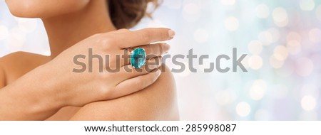 beauty, jewelry, people and accessories concept - close up of woman with cocktail ring on hand over blue holidays lights background
