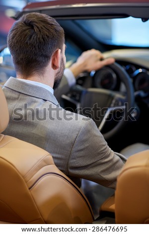 auto business, car sale, lifestyle and people concept - close up of man sitting in cabriolet car at auto show or salon