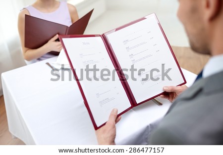 restaurant, food, eating and holiday concept - close up of couple with menu choosing dishes at restaurant