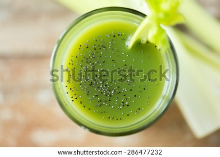healthy eating, organic food and diet concept - close up of fresh green juice with chia seeds and celery on table