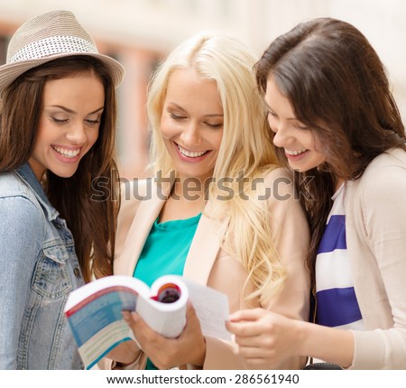 holidays and tourism concept - beautiful girls with city guide book