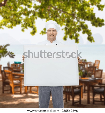 cooking, profession, advertisement and people concept - happy male chef cook holding and showing white blank big board over restaurant lounge on beach