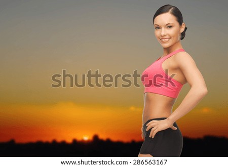 people, fitness and sport concept - happy asian woman posing outdoors over sunset skyline background