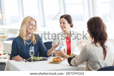 people, holidays, celebration and lifestyle concept - happy women giving birthday present at restaurant