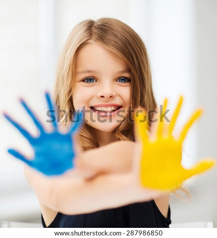 education, school, art and painitng concept - little student girl showing painted hands at school
