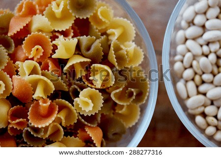 diet, cooking, culinary and carbohydrate food concept - close up of pasta and beans in glass bowls on table