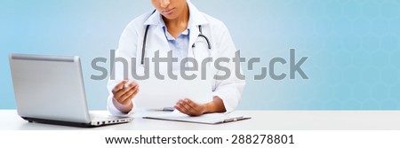 healthcare, medical diagnosis and technology concept - african female doctor with laptop pc computer looking at medical report over blue background