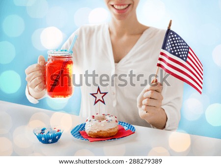 independence day, celebration, patriotism and holidays concept - close up of happy woman with donut celebrating 4th july, holding american flag and drinking juice over blue lights background