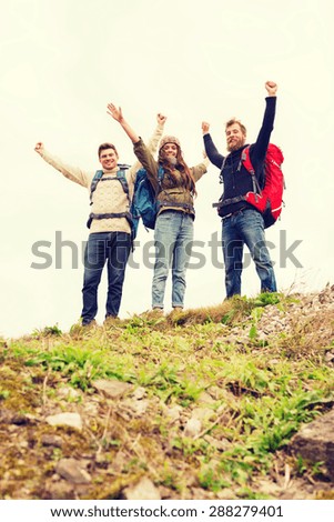 travel, tourism, hike, gesture and people concept - group of smiling friends with backpacks raising hands outdoors