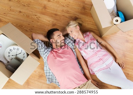 home, people, repair and real estate concept - happy couple with cardboard boxes and stuff lying on floor to new place