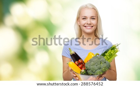 healthy eating, vegetarian food, dieting and people concept - smiling young woman with bowl of vegetables over green natural background