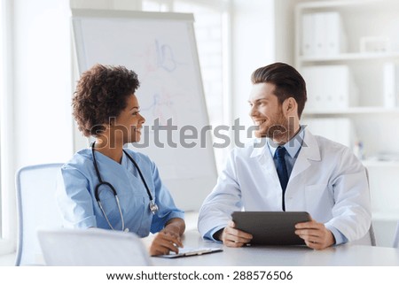 hospital, profession, people and medicine concept - two happy doctors with tablet pc computer meeting and talking at medical office